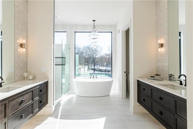 bathroom featuring vanity, a notable chandelier, and plus walk in shower