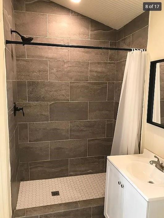 bathroom featuring lofted ceiling, a shower with curtain, and vanity