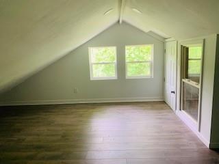 additional living space with lofted ceiling with beams and hardwood / wood-style floors