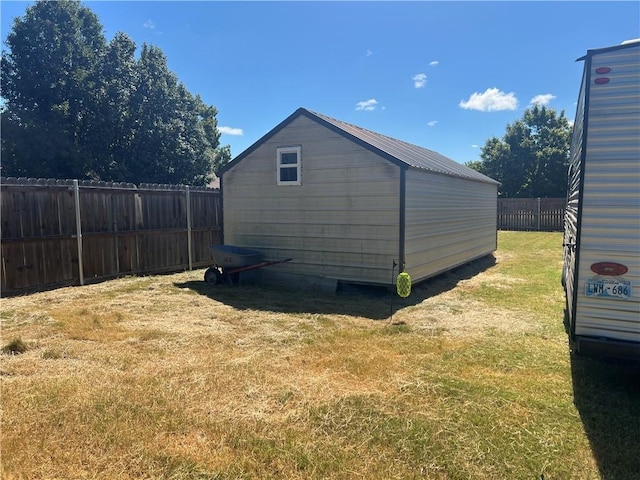 view of side of home featuring a lawn, an outbuilding, a fenced backyard, and a storage shed