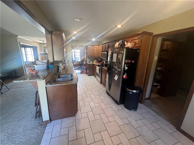 kitchen with a sink, appliances with stainless steel finishes, a healthy amount of sunlight, and stone countertops
