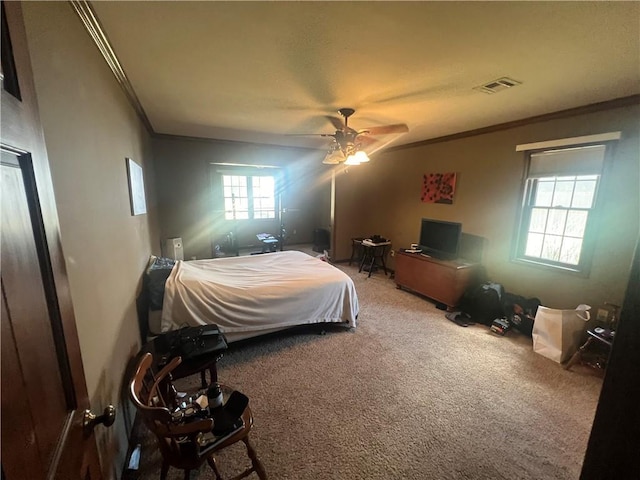 bedroom with carpet floors, crown molding, ceiling fan, and visible vents