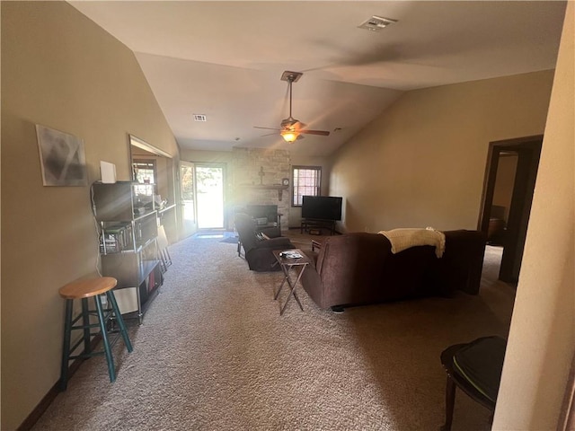 living room featuring carpet, vaulted ceiling, ceiling fan, and a stone fireplace