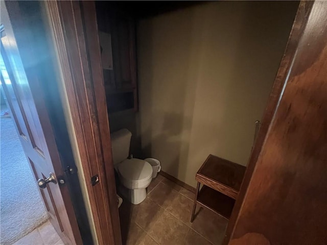 bathroom featuring baseboards, toilet, and tile patterned flooring