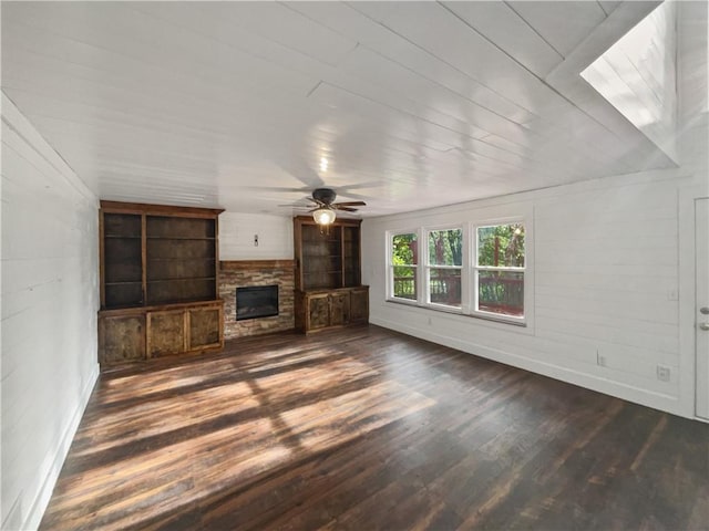 unfurnished living room featuring ceiling fan, dark hardwood / wood-style floors, and a stone fireplace