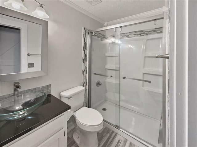 bathroom with a textured ceiling, hardwood / wood-style flooring, walk in shower, vanity, and toilet