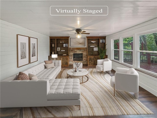 living room with wood-type flooring, ceiling fan, a fireplace, and wooden walls