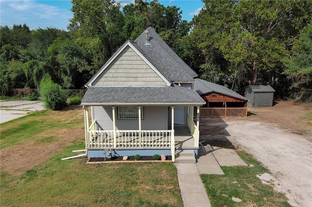 view of front of home featuring a storage unit, covered porch, and a front lawn