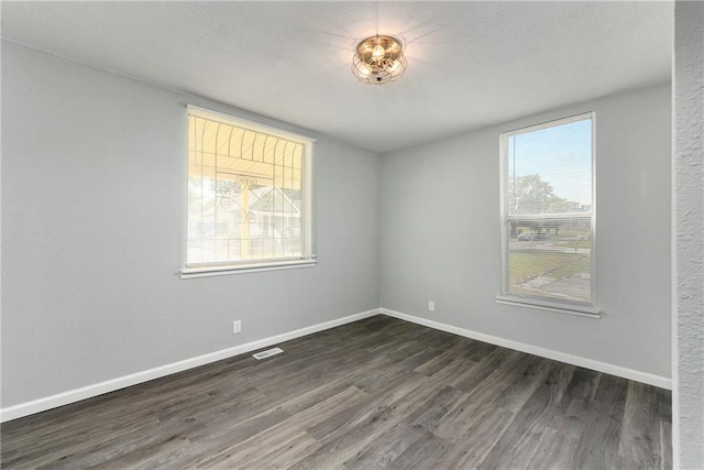 empty room with dark hardwood / wood-style flooring and a healthy amount of sunlight