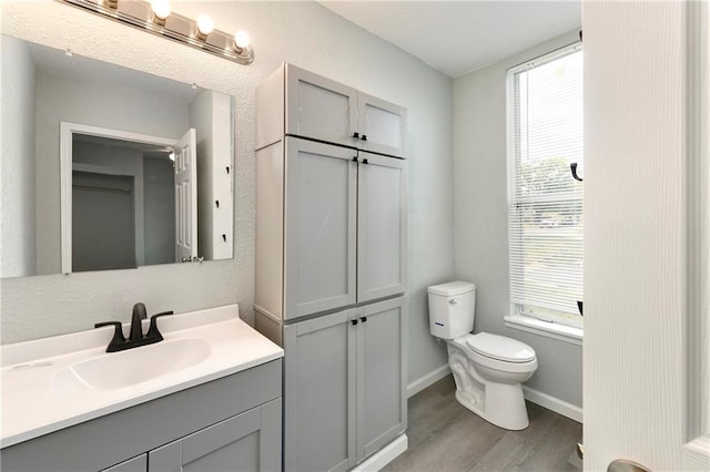 bathroom featuring wood-type flooring, vanity, toilet, and a wealth of natural light