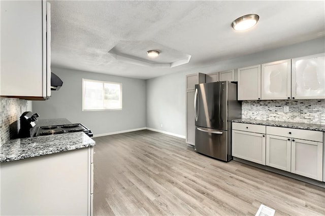 kitchen with stainless steel fridge, tasteful backsplash, range, exhaust hood, and light hardwood / wood-style floors