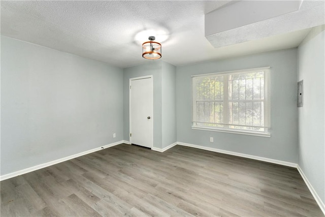 empty room with a notable chandelier, wood-type flooring, and a textured ceiling