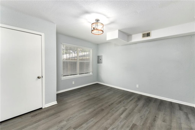 unfurnished room with a textured ceiling and dark wood-type flooring