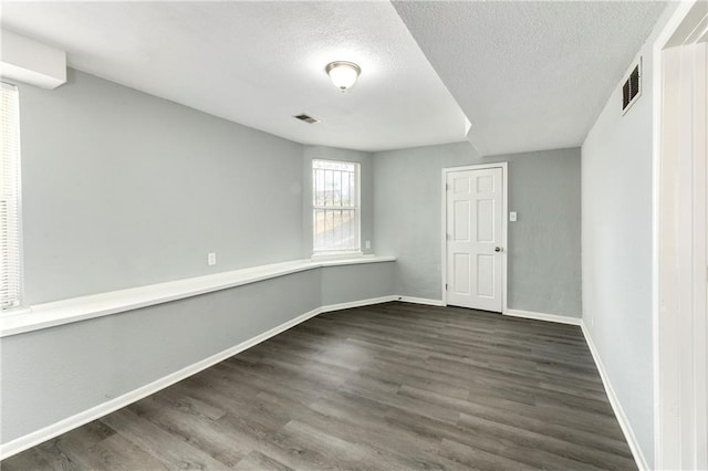 empty room featuring a textured ceiling and dark hardwood / wood-style floors