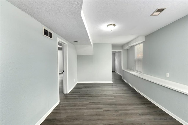 unfurnished room with a textured ceiling and dark hardwood / wood-style flooring