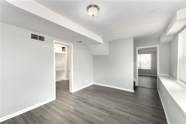 spare room featuring a textured ceiling and dark hardwood / wood-style floors