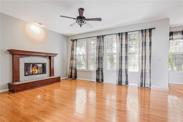 unfurnished living room with ceiling fan, plenty of natural light, light wood-type flooring, and a fireplace