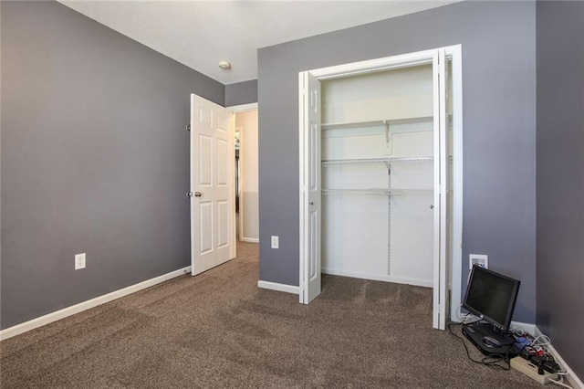 unfurnished bedroom featuring dark carpet and a closet