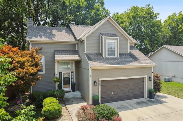 view of front of home featuring concrete driveway, a shingled roof, a garage, central AC unit, and a chimney