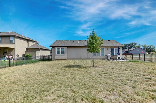 rear view of property featuring a yard, a patio, and a fenced backyard