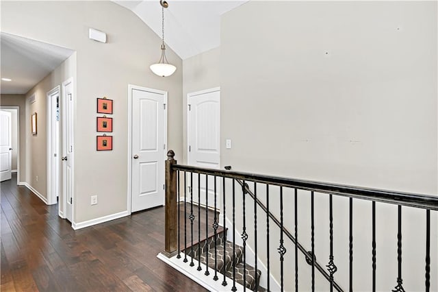 corridor with dark wood-style floors, baseboards, high vaulted ceiling, and an upstairs landing