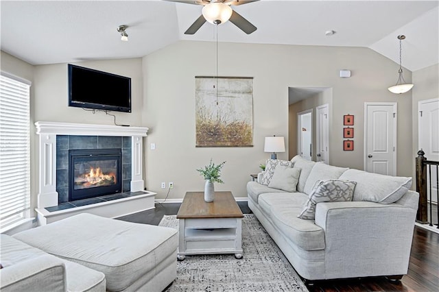 living room with dark wood-style floors, baseboards, vaulted ceiling, and a tile fireplace