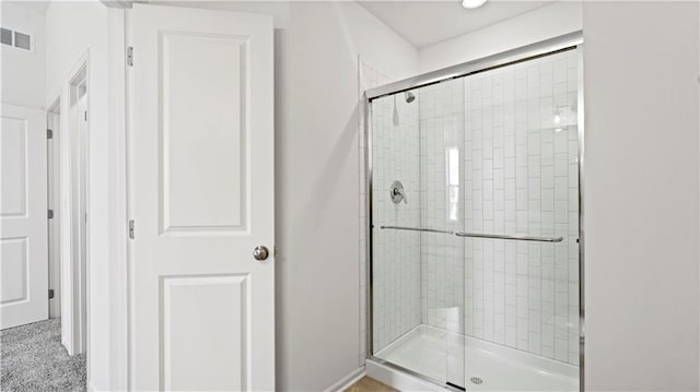 bathroom with a shower stall and visible vents