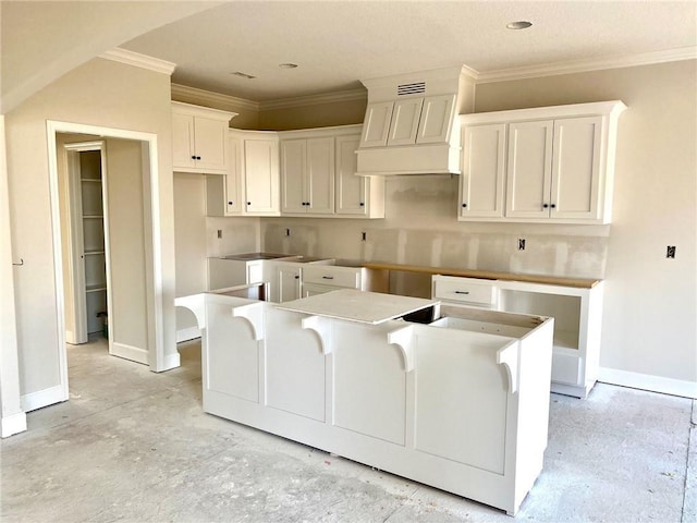 kitchen featuring white cabinetry, baseboards, ornamental molding, custom exhaust hood, and a center island