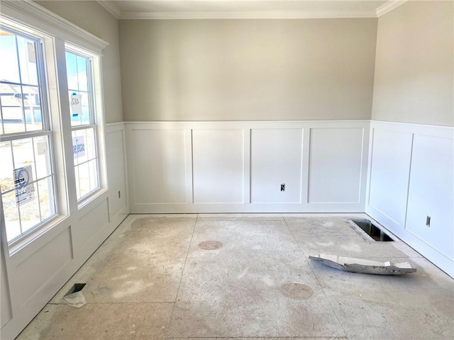 empty room featuring wainscoting, plenty of natural light, visible vents, and a decorative wall