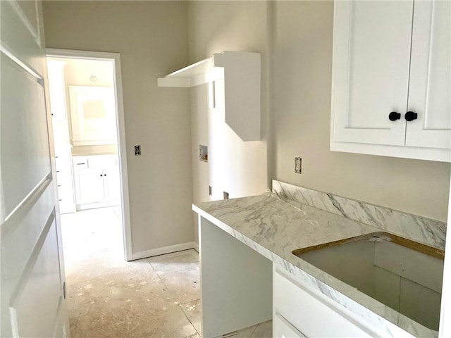 kitchen featuring white cabinets, a sink, and baseboards