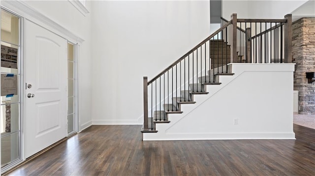 foyer entrance featuring stairs, baseboards, a high ceiling, and wood finished floors