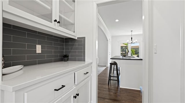 bar featuring dark wood-style floors, recessed lighting, decorative backsplash, a sink, and baseboards