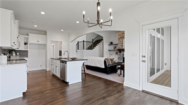 kitchen featuring dishwasher, dark wood-style flooring, arched walkways, and decorative backsplash