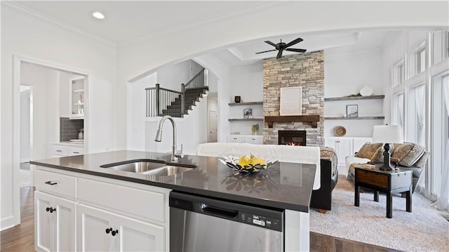 kitchen featuring dark countertops, a fireplace, a sink, and stainless steel dishwasher