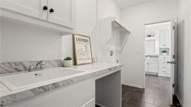 washroom featuring hookup for a washing machine, cabinet space, a sink, electric dryer hookup, and baseboards