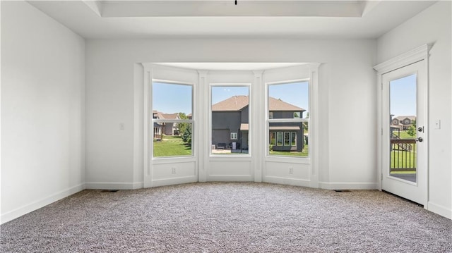 unfurnished room featuring a raised ceiling, carpet flooring, visible vents, and baseboards