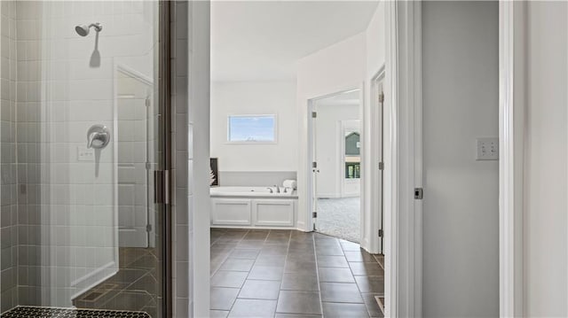 bathroom with a stall shower, a garden tub, and tile patterned floors