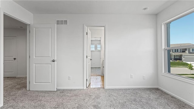 unfurnished bedroom with carpet floors, visible vents, and baseboards