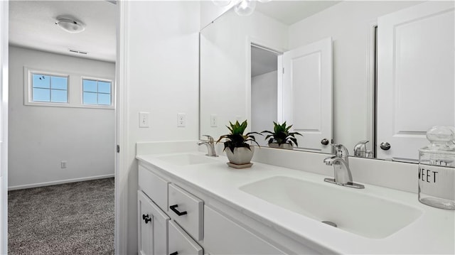 bathroom featuring double vanity, baseboards, and a sink