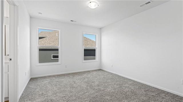 empty room with carpet floors, visible vents, and baseboards