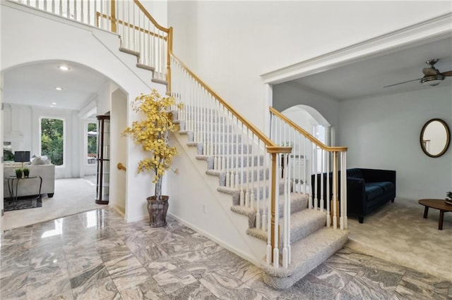 stairs with ceiling fan and carpet floors