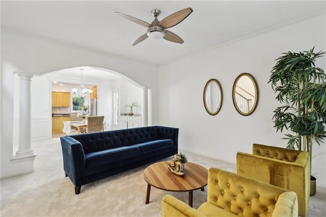 living room with ceiling fan with notable chandelier, ornamental molding, light carpet, and ornate columns