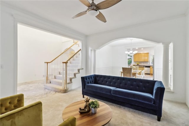 living room with ceiling fan with notable chandelier, light colored carpet, and crown molding