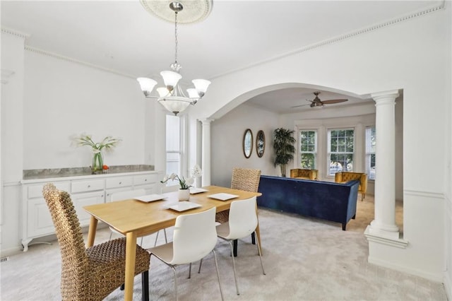 dining space with light carpet, ceiling fan with notable chandelier, and ornate columns