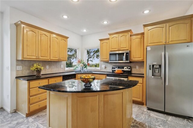 kitchen with dark stone counters, a kitchen island, appliances with stainless steel finishes, and tasteful backsplash