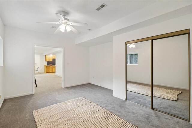 unfurnished bedroom featuring a closet, ceiling fan, and light colored carpet