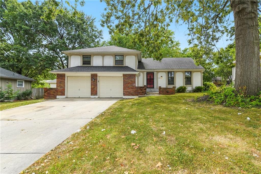 split level home featuring a front yard, cooling unit, and a garage