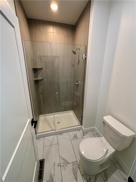 bathroom featuring a shower with door and toilet