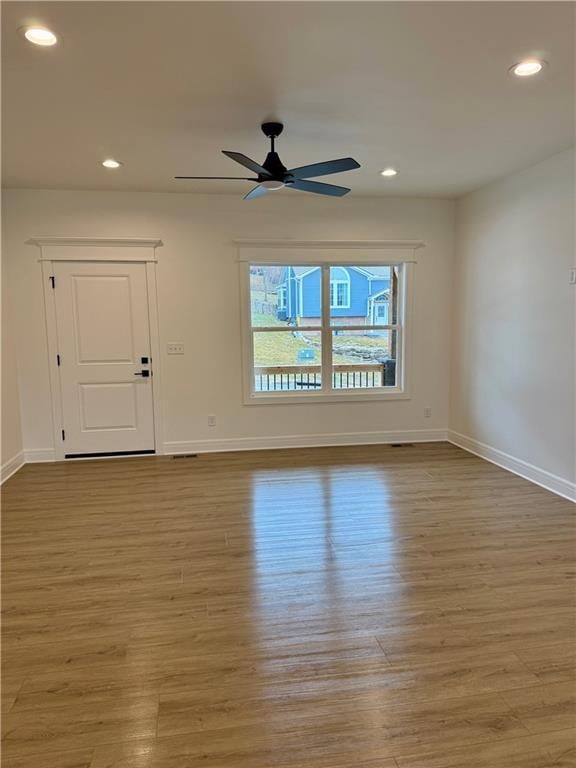 empty room with ceiling fan and light hardwood / wood-style floors