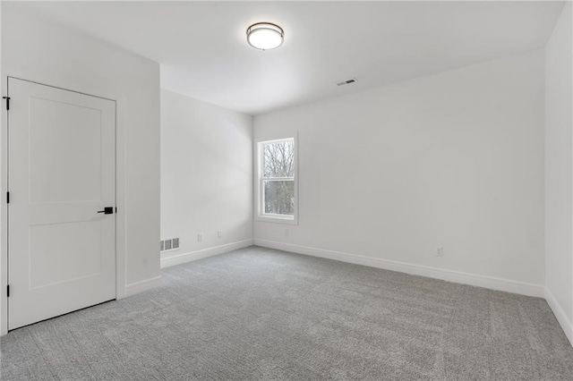 spare room with carpet, visible vents, and baseboards